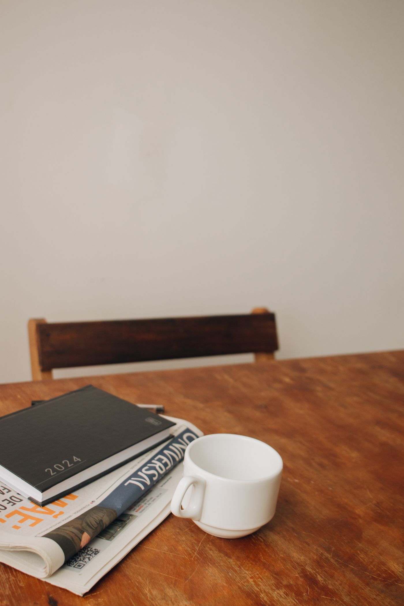Schreibtisch mit Zeitung, Notizbuch und Kaffeetasse