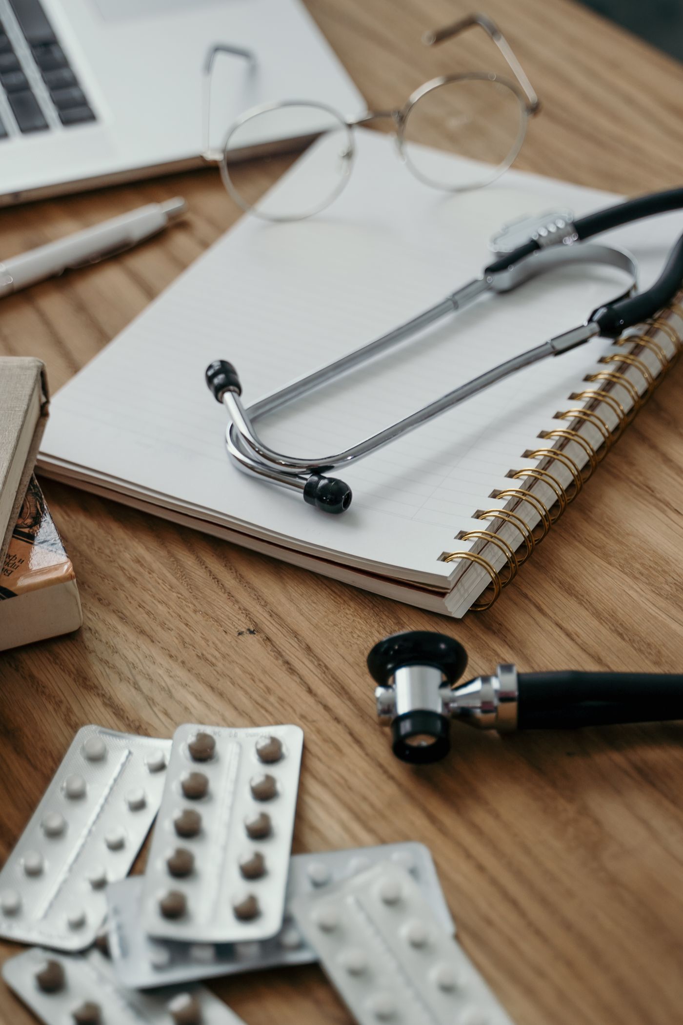 Stethoskop, Notizbuch und Tabletten auf einem Arzttisch